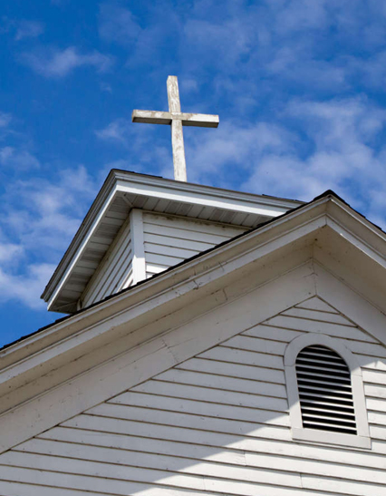 Church steeple with cross against blue sky.