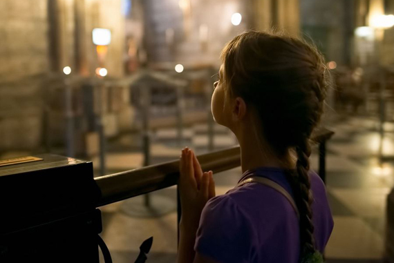 Young girl praying in a cathedral.