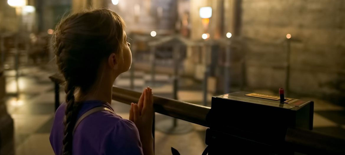 Girl praying inside a cathedral.