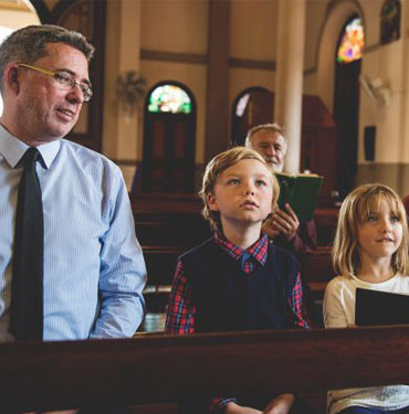Family sitting in church pews, listening attentively.