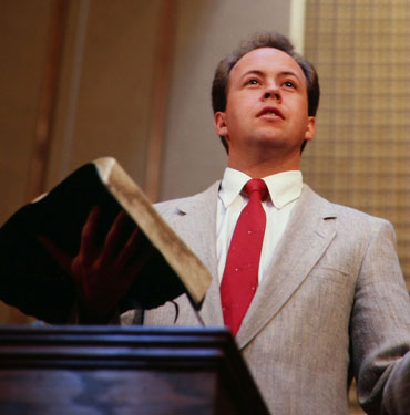 Man speaking while holding a book.