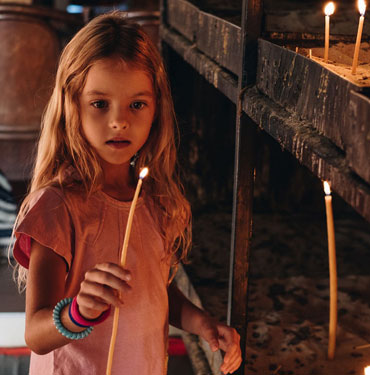 Girl lighting a candle in a dim setting.