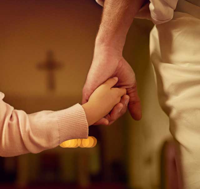 Two hands clasped together, adult and child.