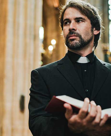Man in clerical attire holding a book.