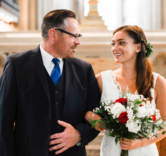 Smiling couple in wedding attire indoors.