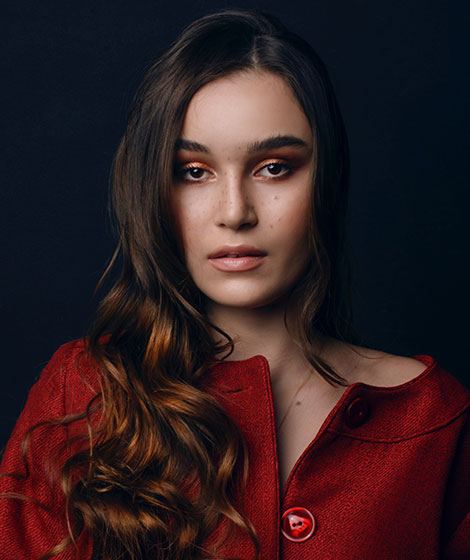 Young woman with long hair in red coat.