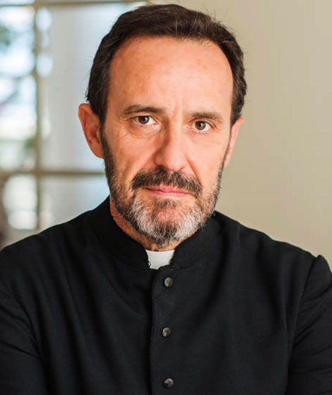 Middle-aged man in a black clerical outfit.